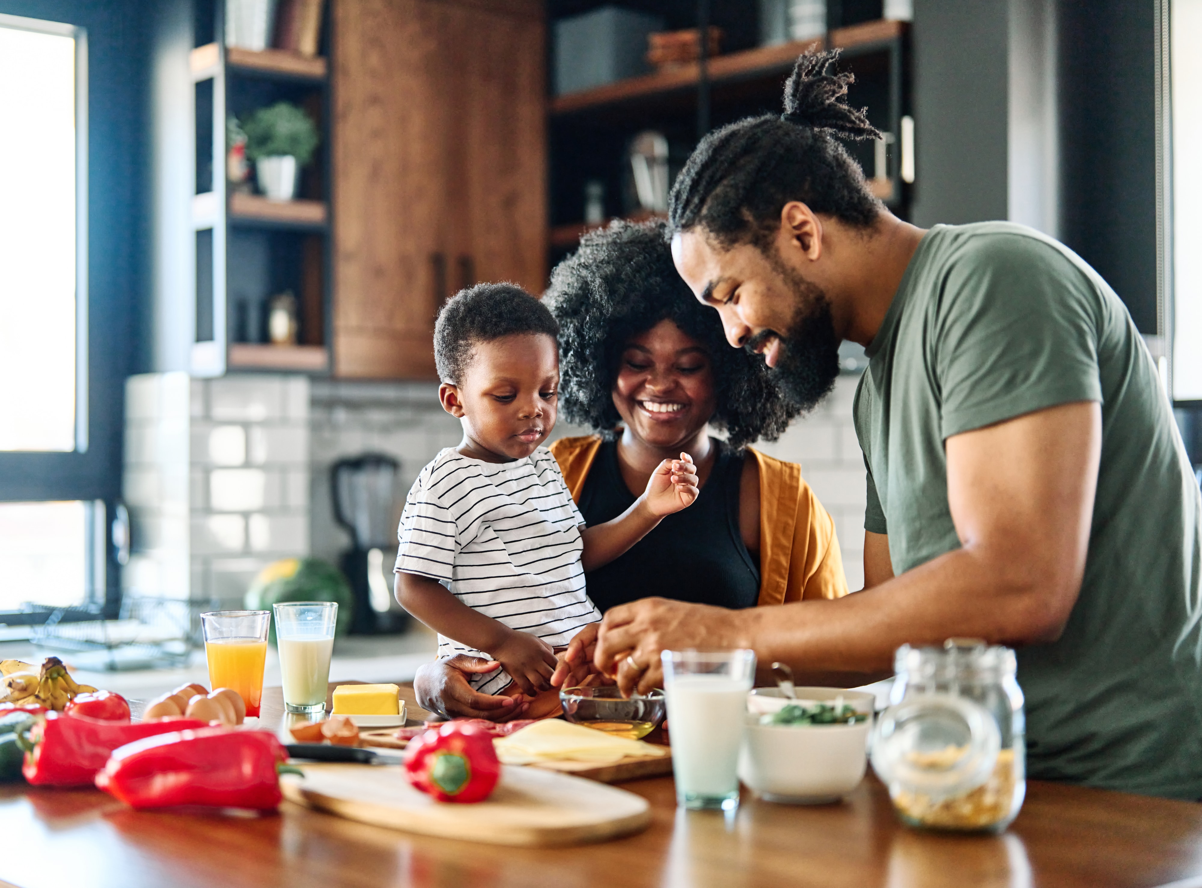 mother, father and son preparing and eating breakfast in the kitchen at home