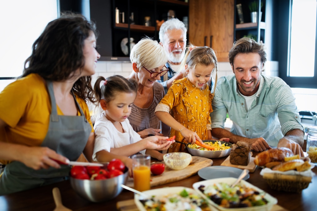 cheerful family gathered in the kitchen preparing food together