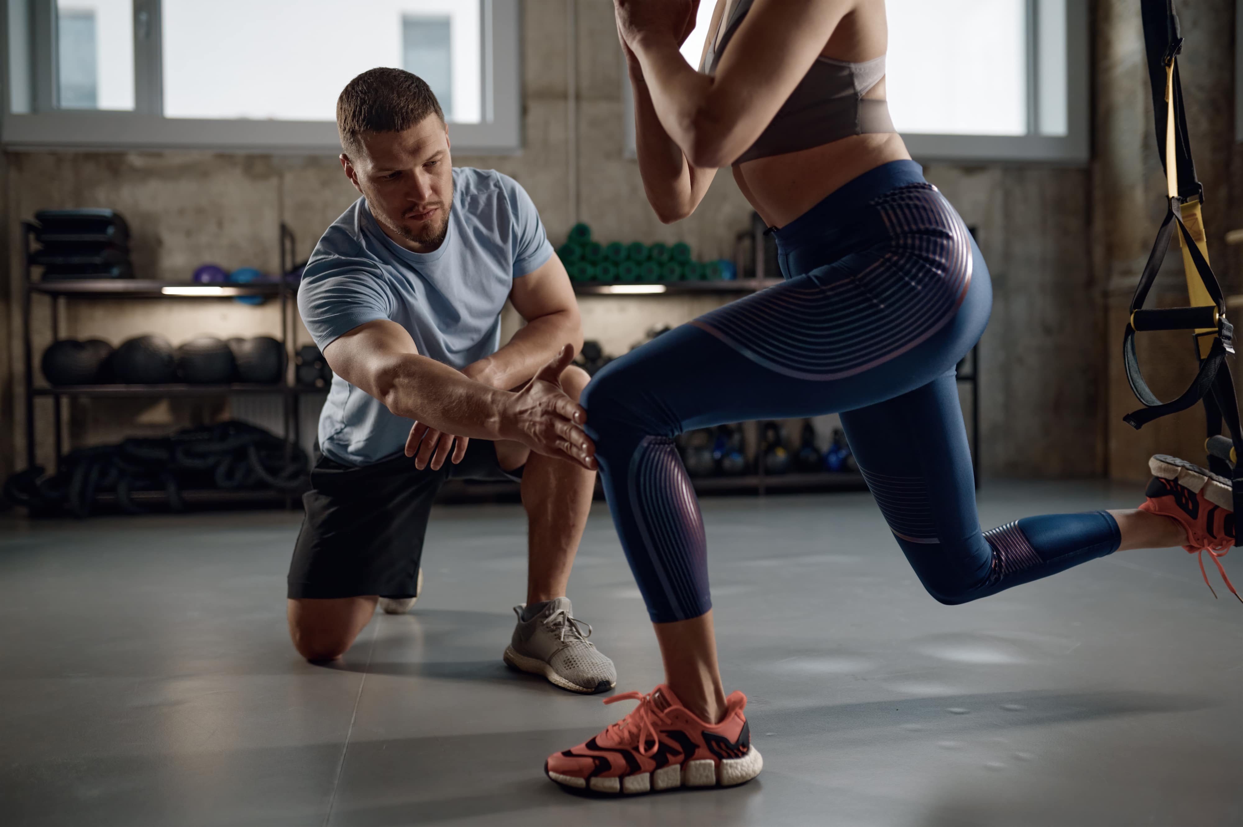 AFPA Certified Personal Trainer Coaching a Client in the Gym through a Lunge using the TRX