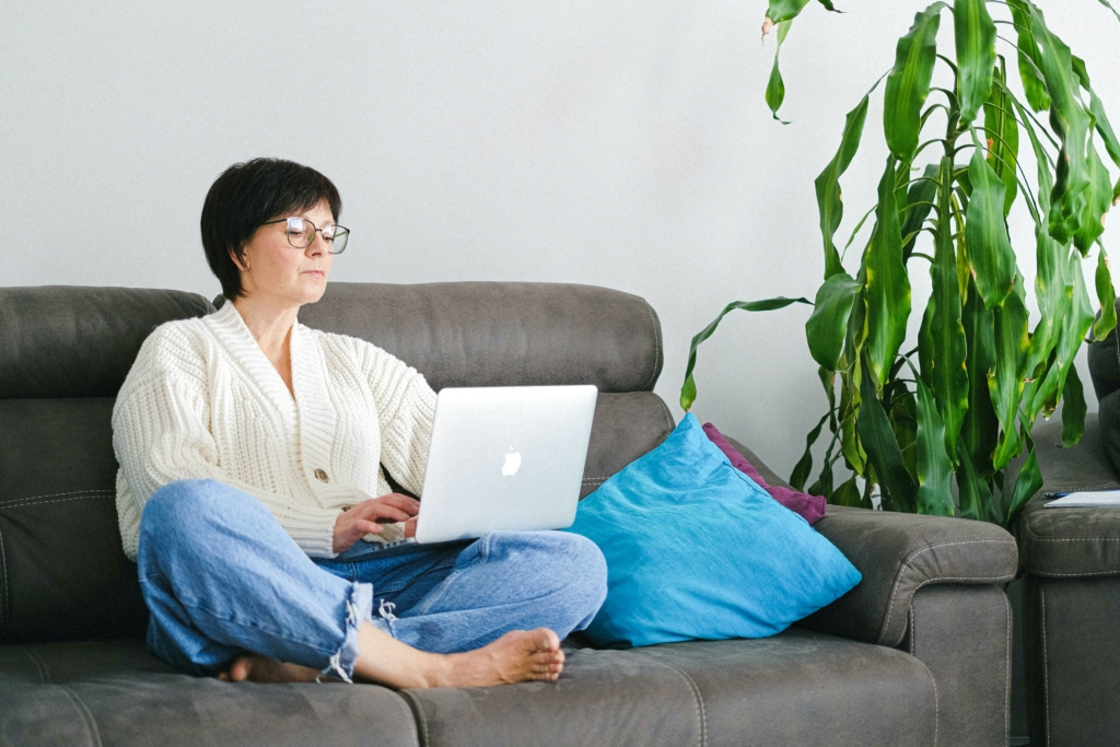 woman on couch with laptop taking the menopause nutrition course by afpa